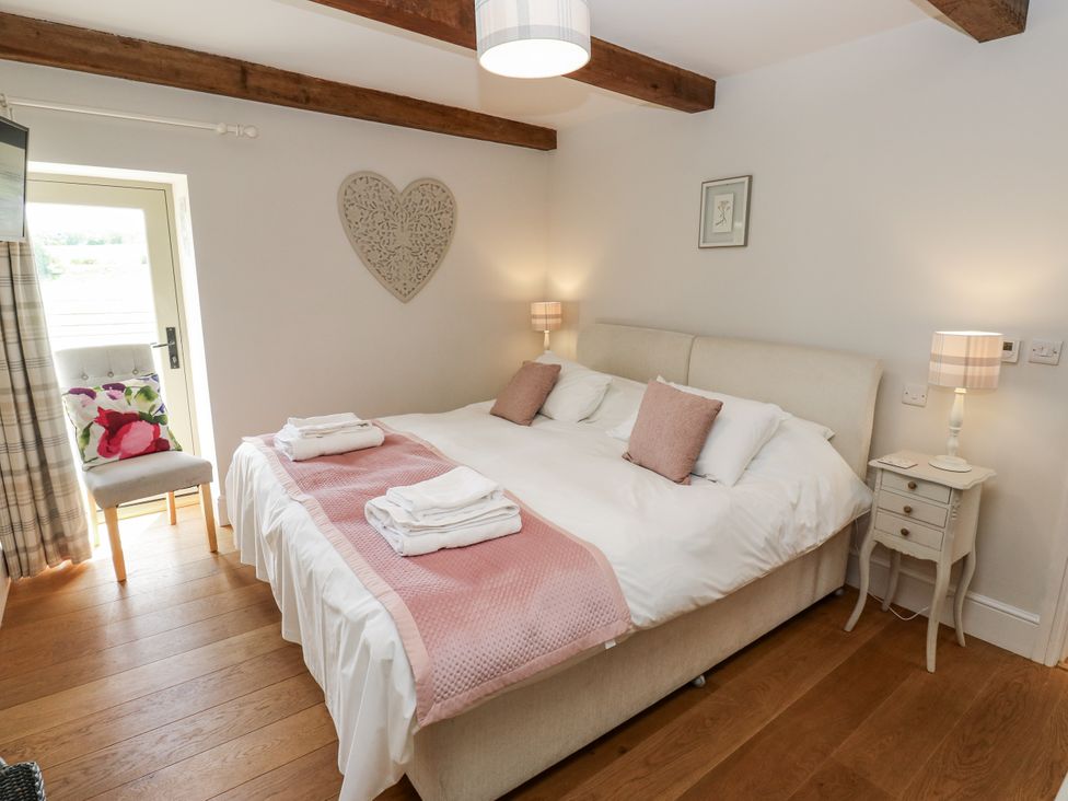 A bedroom with a bed, nightstand, and chair at Crane Field Laithe, Otterburn, North Yorkshire