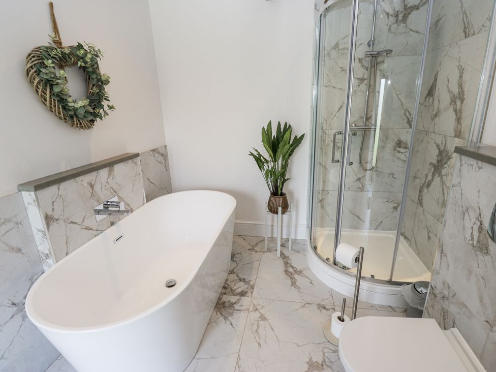 A bathroom featuring a bathtub, shower, toilet and plant at Crane Field Laithe, Otterburn, North Yorkshire