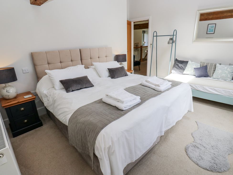 A bedroom with a large bed and a sofa at Crane Field Laithe in Otterburn, North Yorkshire