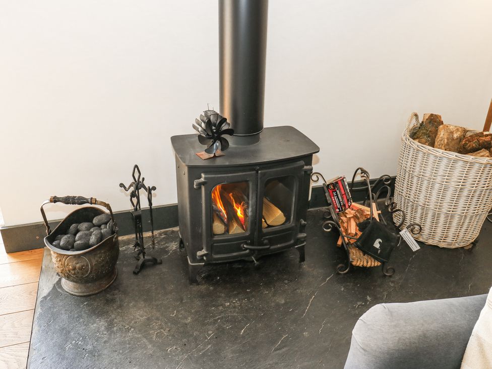 A wood stove with fire and decorative items at Crane Field Laithe in Otterburn, North Yorkshire