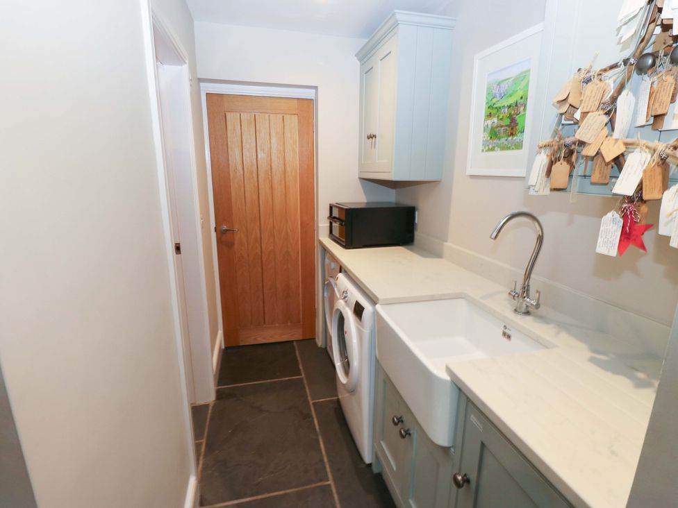 A laundry room with a washing machine, sink, and microwave at Crane Field Laithe, Otterburn, North Yorkshire