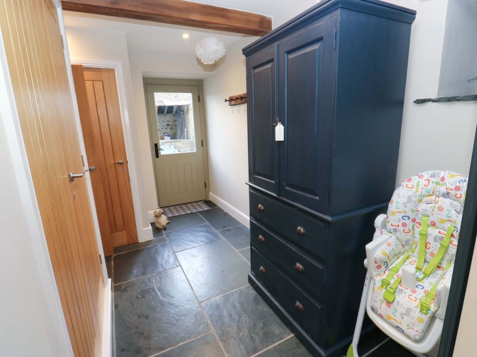 A hallway with a wardrobe and a high chair at Crane Field Laithe in Otterburn, North Yorkshire