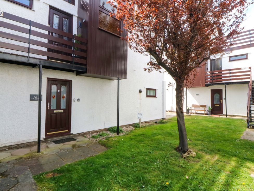 An outdoor area with a tree and doors at Beach House (Ty Traeth) in Deganwy