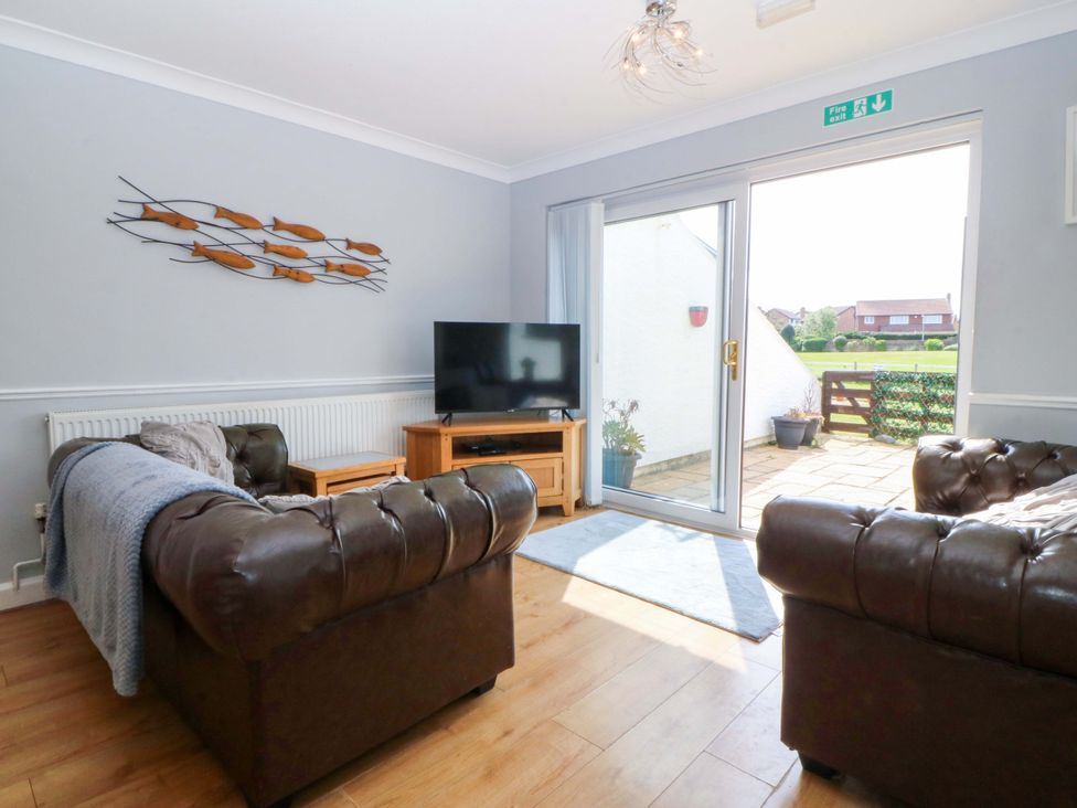 A living room with a sofa and a television at Beach House (Ty Traeth) in Deganwy
