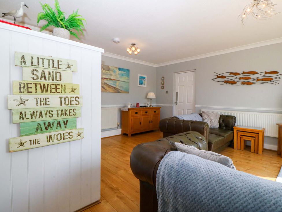A living room with a decorative sign and wooden furniture at Beach House (Ty Traeth) in Deganwy