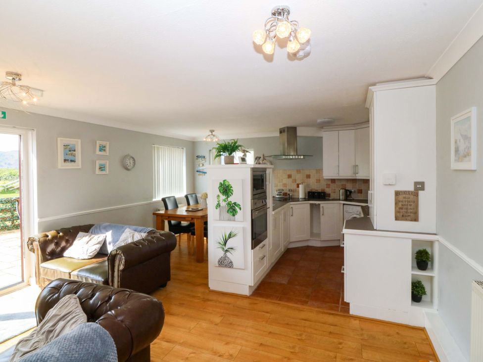 A kitchen with a dining table and sofa at Beach House (Ty Traeth) in Deganwy