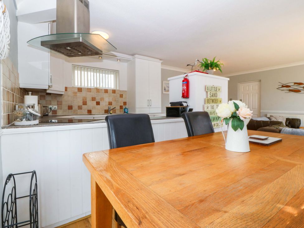 A kitchen with a wooden table and chairs at Beach House (Ty Traeth) Deganwy