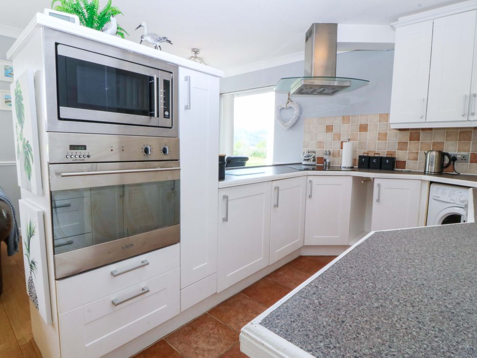 A kitchen with appliances including a microwave and oven at Beach House (Ty Traeth) Deganwy