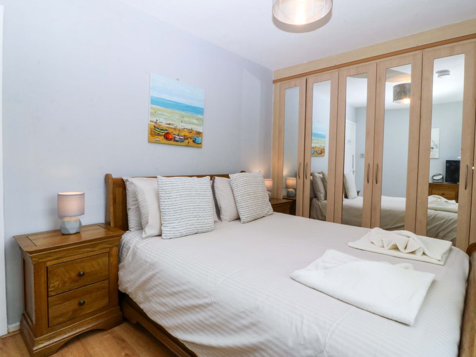 A bedroom with a bed and lamp at Beach House (Ty Traeth) Deganwy