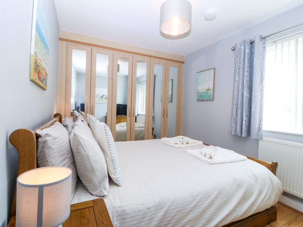 A bedroom with a bed and wardrobe at Beach House (Ty Traeth) Deganwy