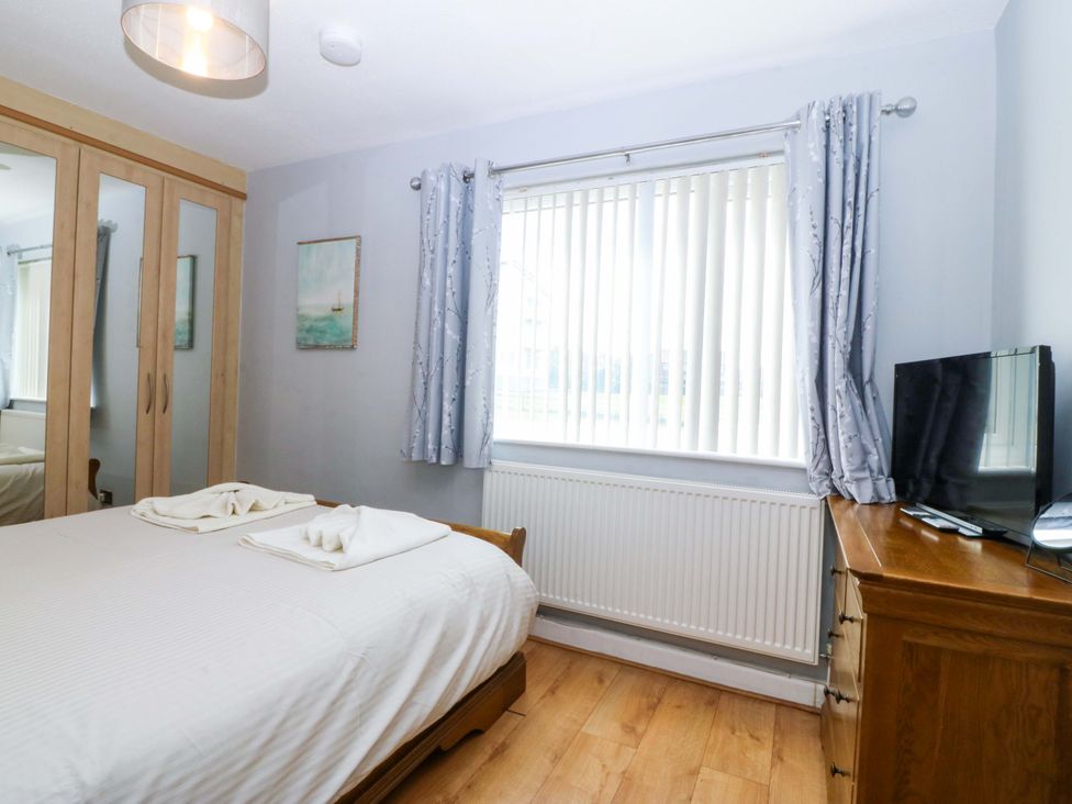 A bedroom with a bed and wardrobe at Beach House (Ty Traeth) in Deganwy