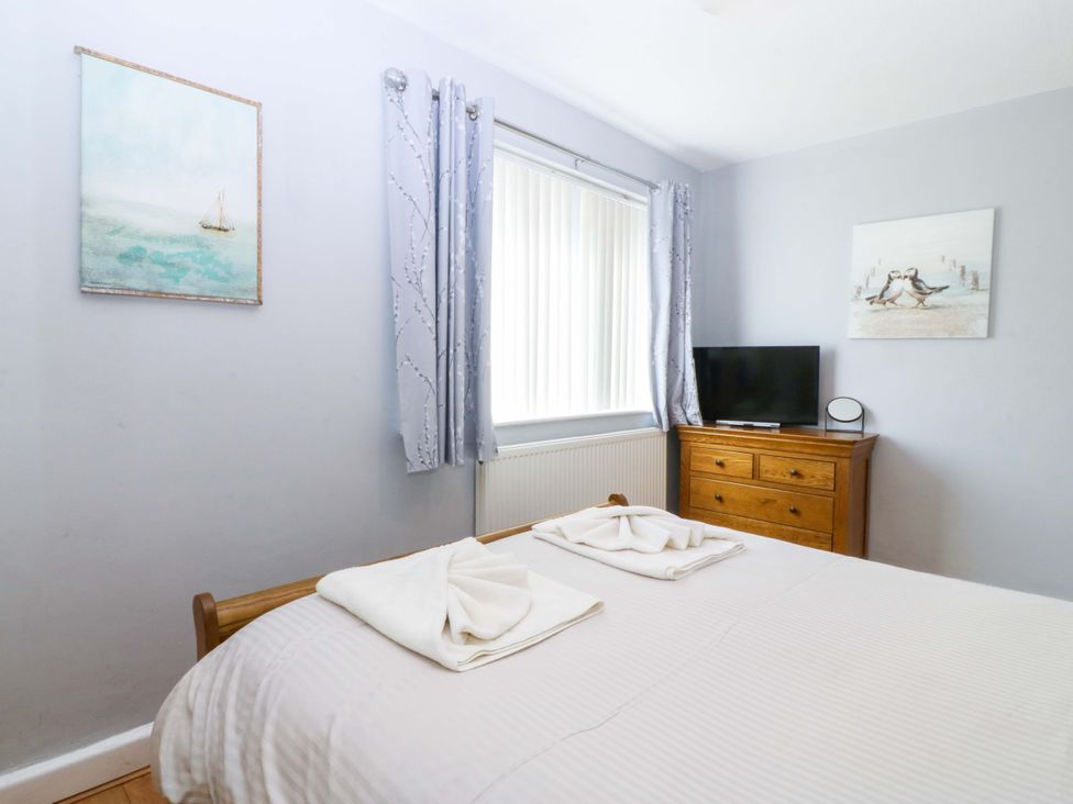 A bedroom with a bed and television at Beach House (Ty Traeth) Deganwy