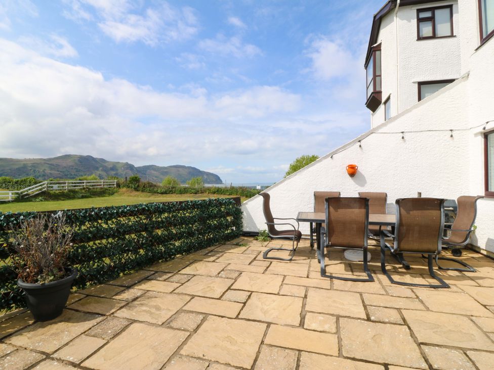 An outdoor patio with a table and chairs at Beach House (Ty Traeth) Deganwy