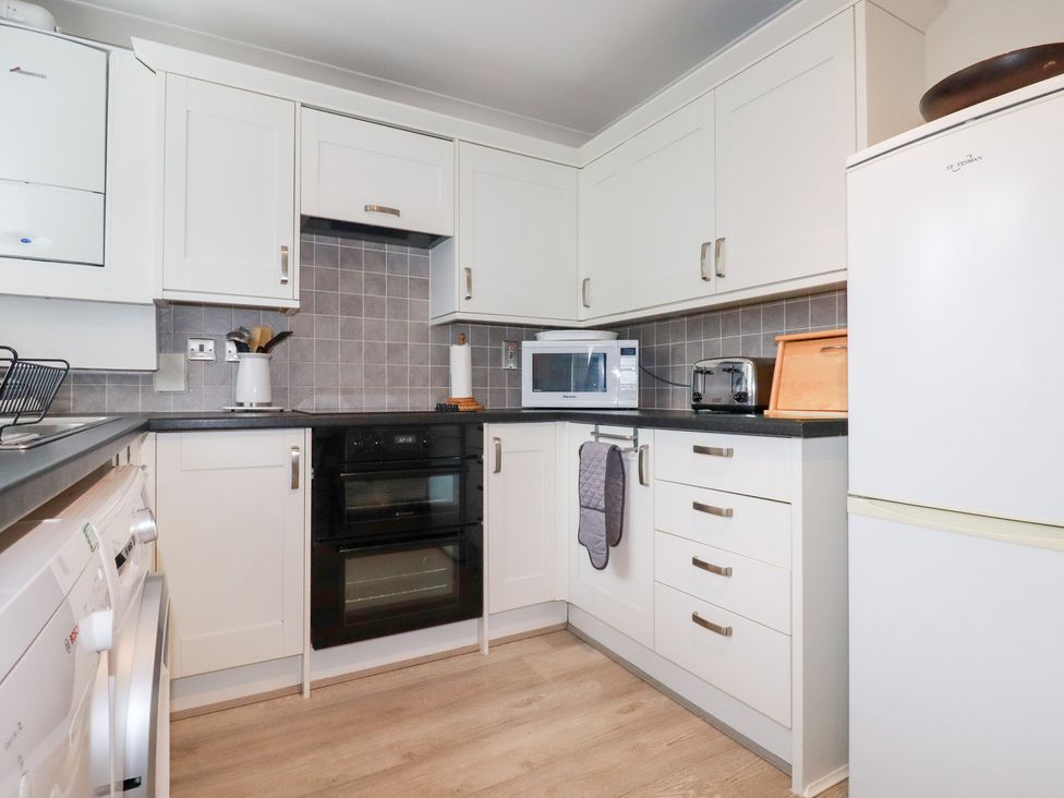 A kitchen with appliances and cabinets at Gull Cottage in Padstow