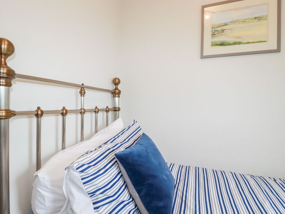 A bed with striped bedding and a painting on the wall at Gull Cottage in Padstow