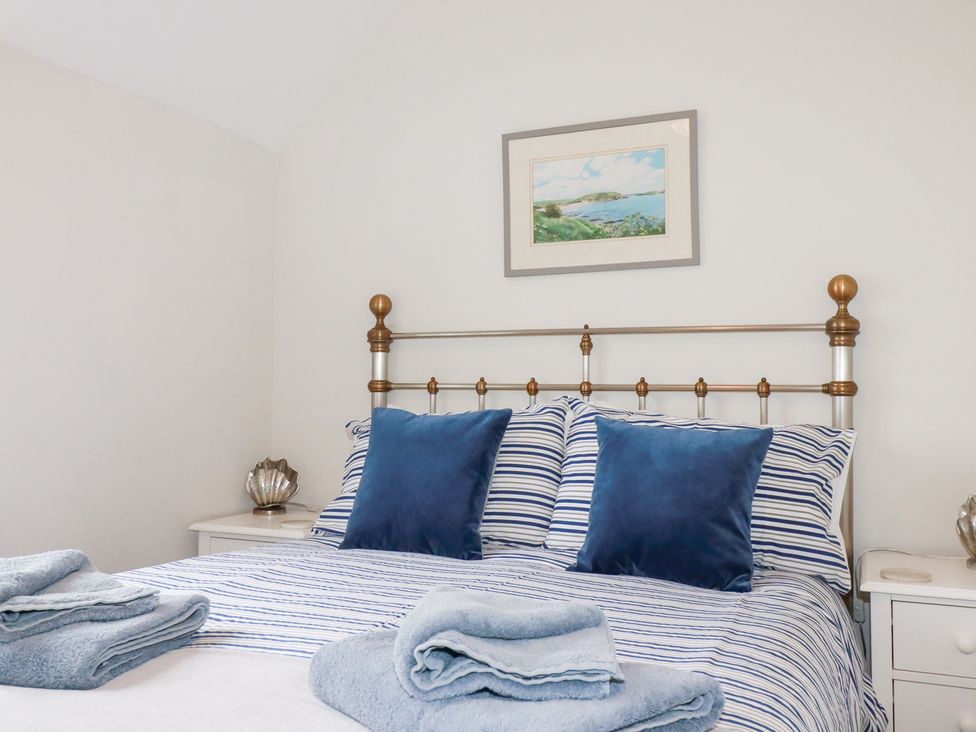 A bedroom with a bed, pillows, and a picture frame at Gull Cottage in Padstow