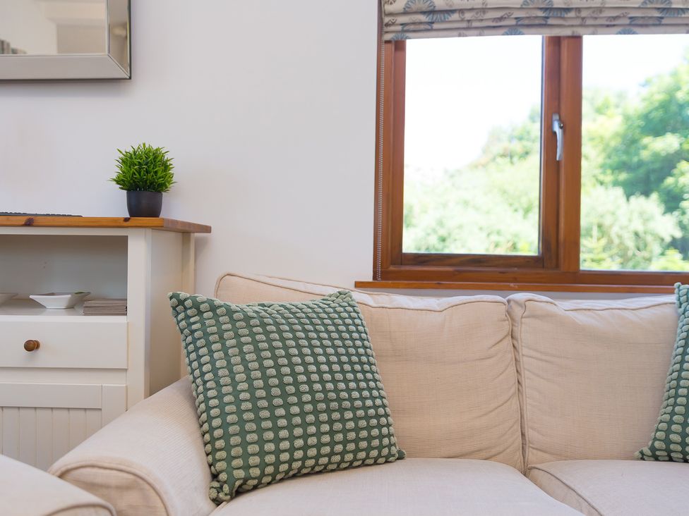 A living room with a sofa and window at Costentyn, Tor Down Quarry St Breward