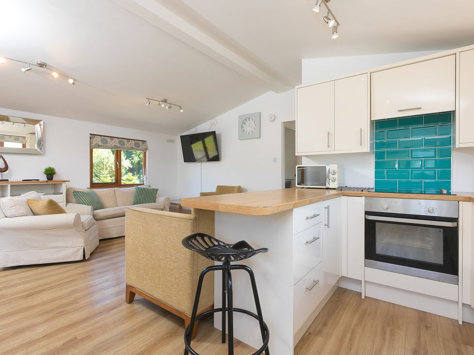 A living room with kitchen area and seating at Costentyn, Tor Down Quarry in St Breward