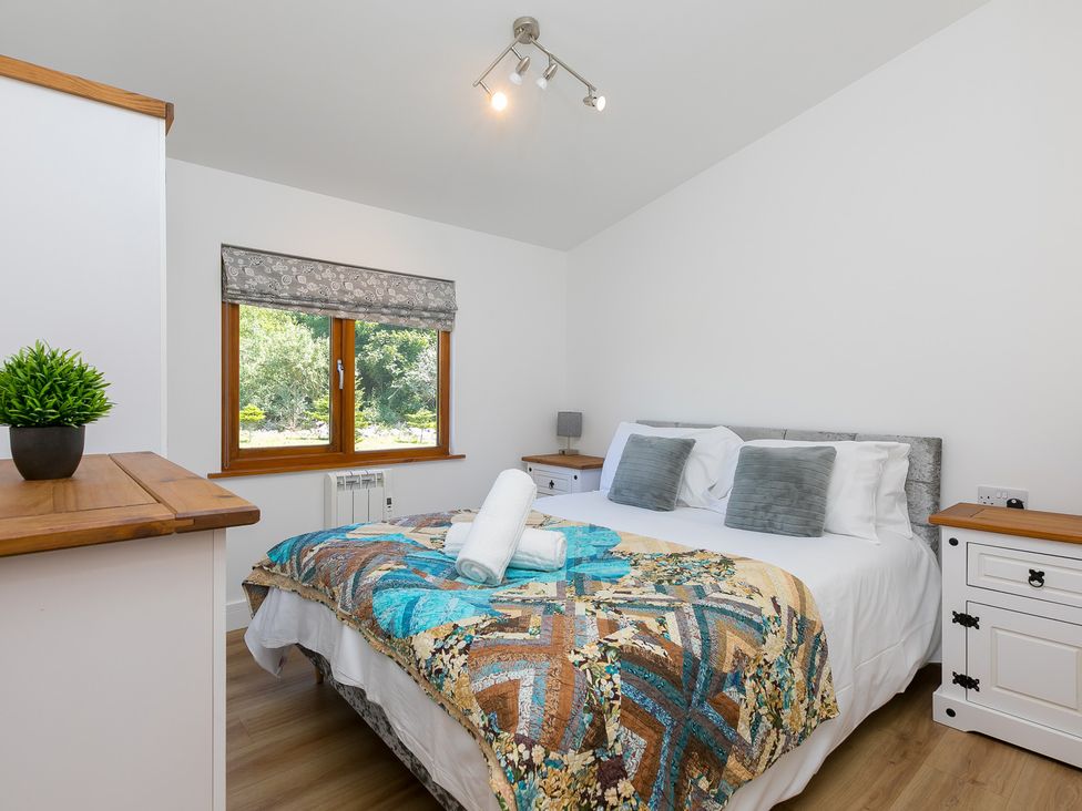 A bedroom with a bed and windows at Costentyn, Tor Down Quarry in St Breward