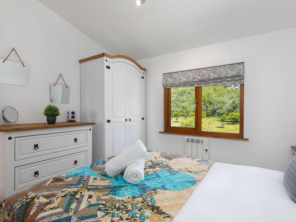 A bedroom with a bed and a wardrobe at Costentyn, Tor Down Quarry in St Breward