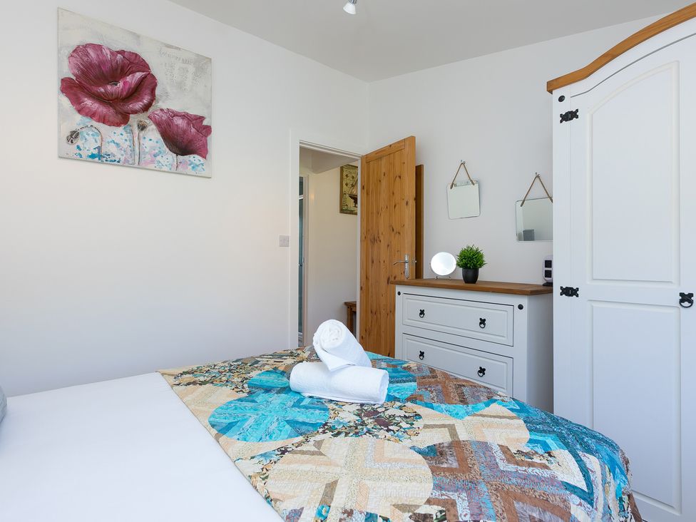 A bedroom with a bed and white wardrobe at Costentyn, Tor Down Quarry St Breward