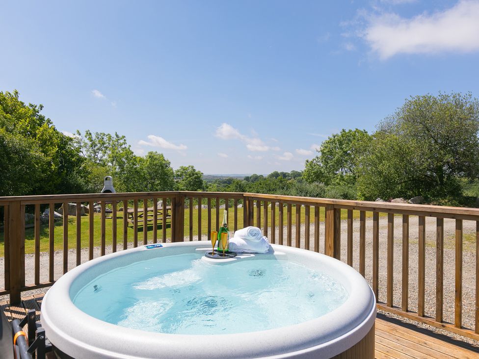 A hot tub with a bottle and towel in outdoor area at Costentyn, Tor Down Quarry St Breward
