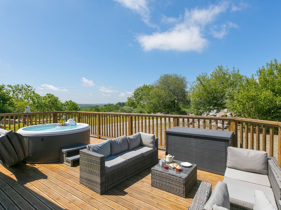 A seating area with a hot tub on a wooden deck at Costentyn, Tor Down Quarry St Breward