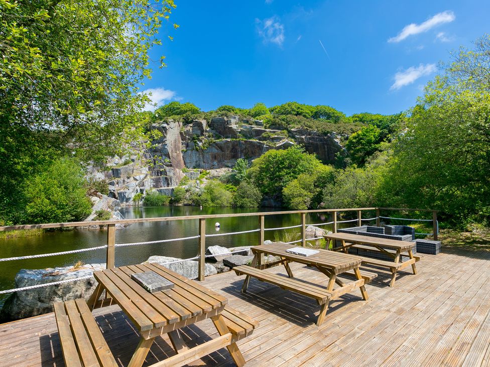 A deck with tables and benches overlooking water and rocks at Costentyn, Tor Down Quarry St Breward