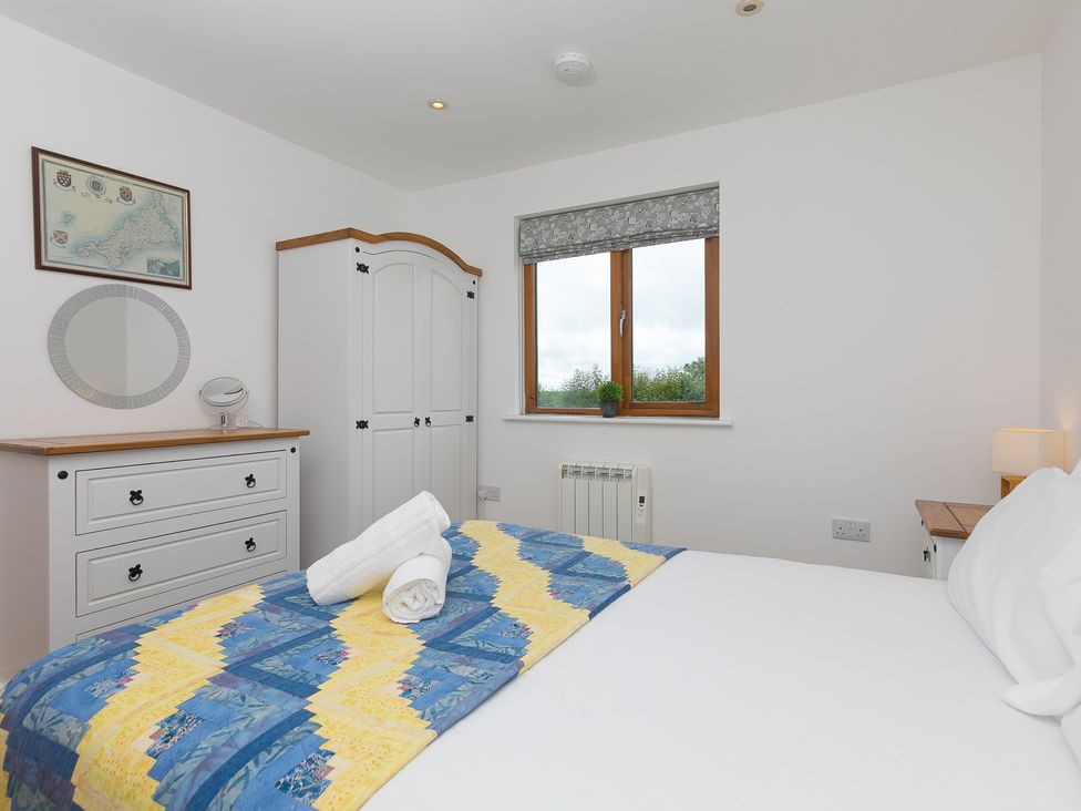 A bedroom with a bed, dresser, and window at Tressa, Tor Down Quarry St Breward