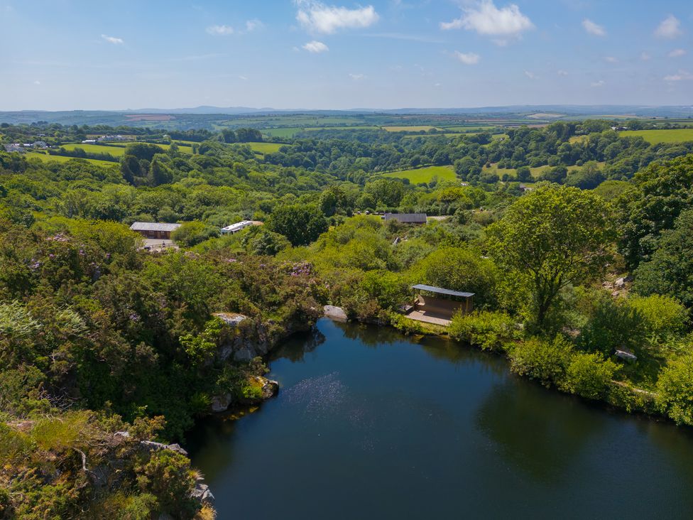 An aerial view of a pond surrounded by trees and countryside at Tressa, Tor Down Quarry St Breward