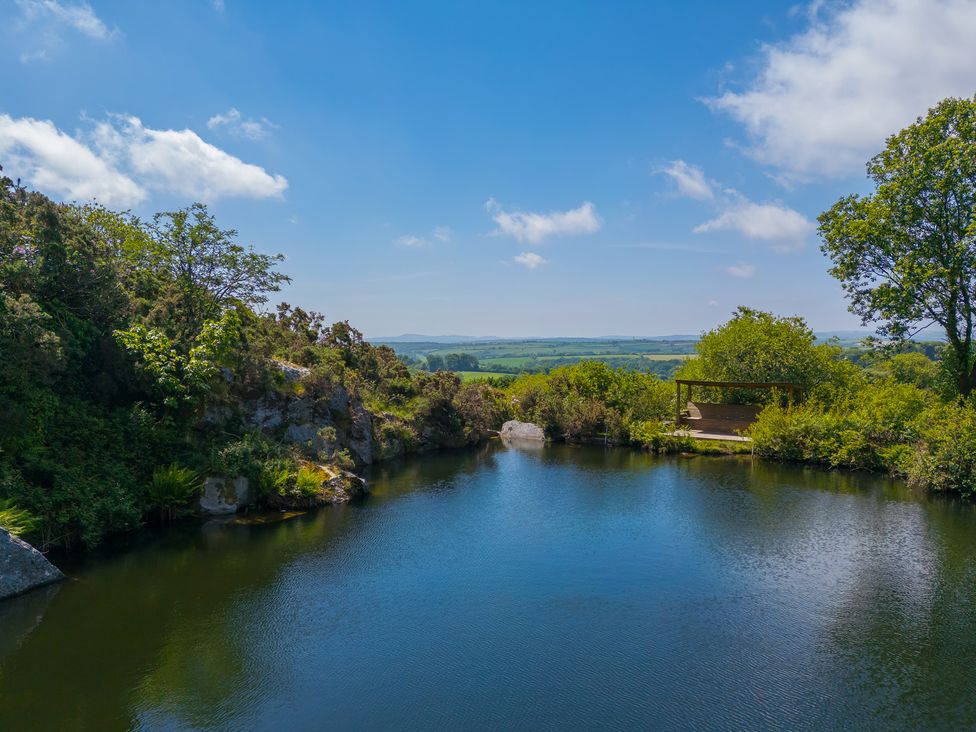 A scenic view of a pond with trees and rocks at Tressa, Tor Down Quarry St Breward