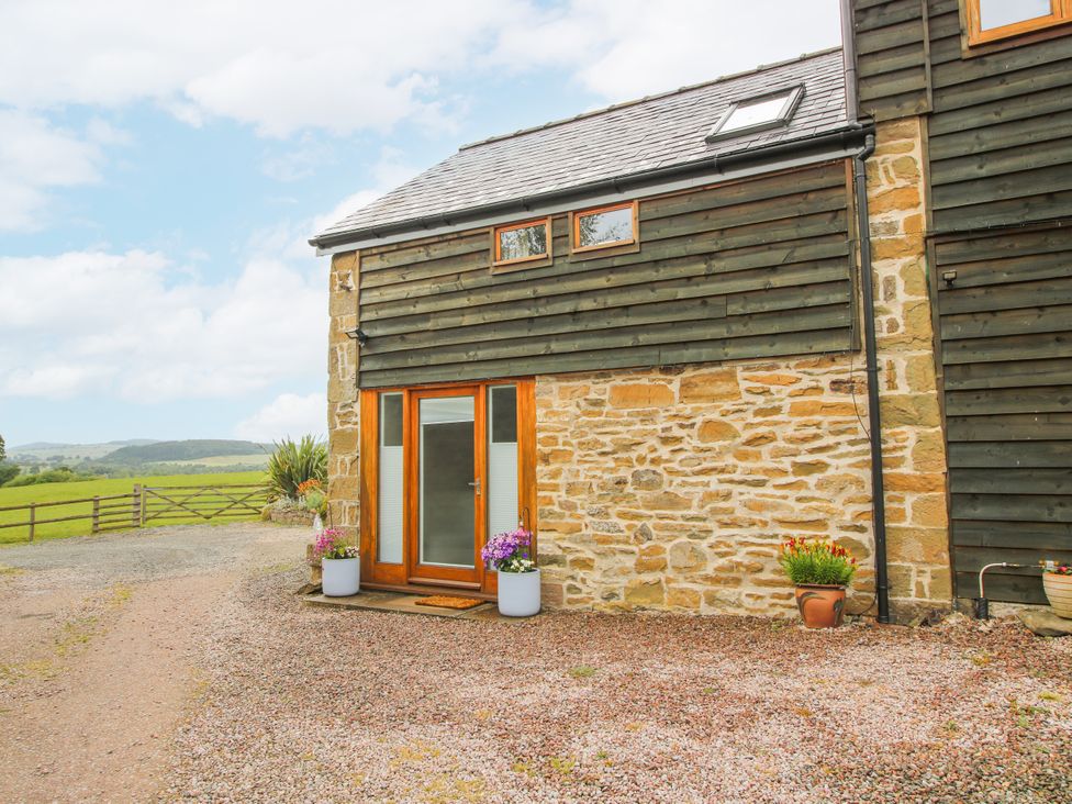 An exterior view of a house with a door and flower pots at The Hay Loft in Craven Arms
