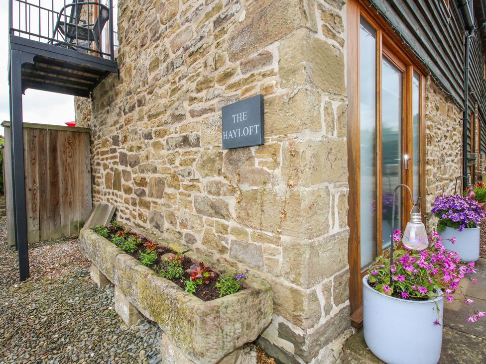An outdoor view of The Hay Loft with stone walls and flower planters in Craven Arms