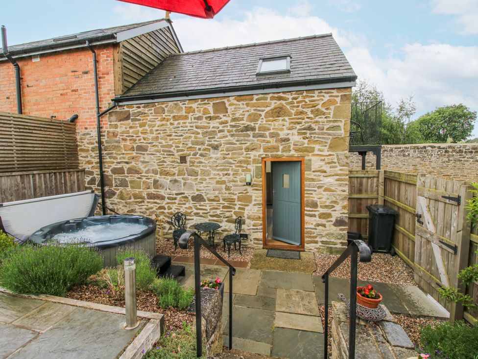 An outdoor area with a hot tub and seating at The Hay Loft in Craven Arms