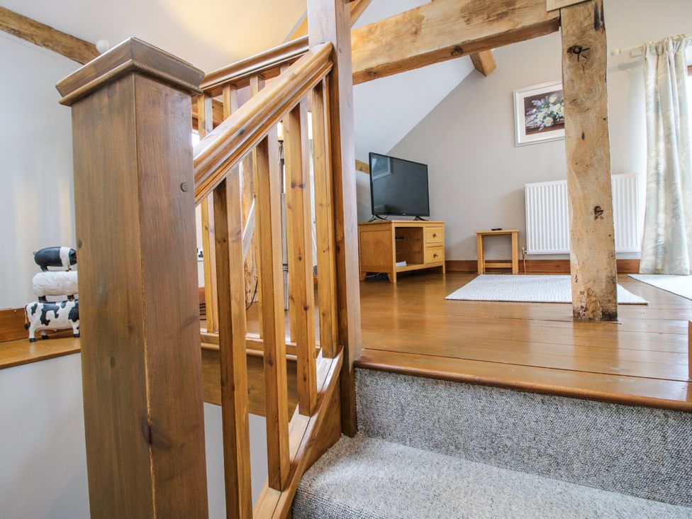 A living room with a staircase and wooden beams at The Hay Loft in Craven Arms