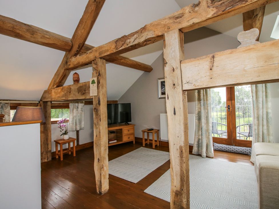 A living room with wooden beams and a television at The Hay Loft in Craven Arms