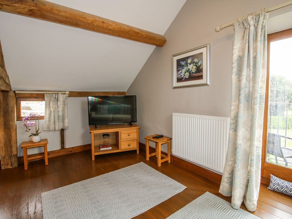 A living room with a television and window at The Hay Loft in Craven Arms