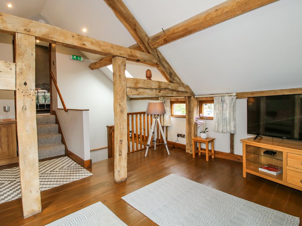 A living room with wooden beams and a television at The Hay Loft in Craven Arms