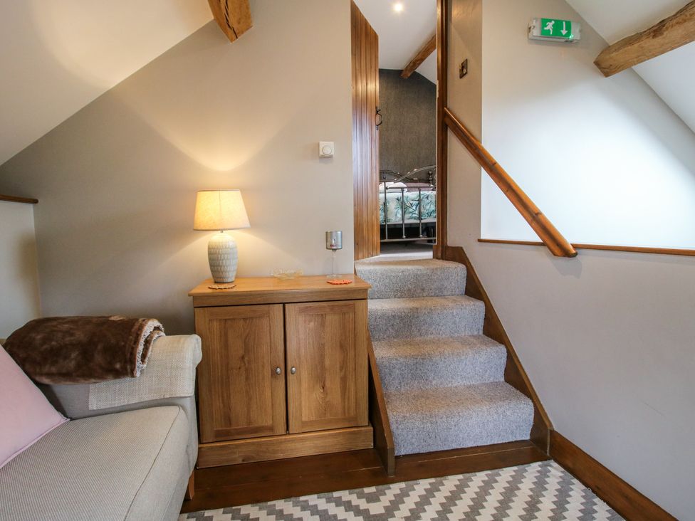 A hallway with a staircase and a cabinet at The Hay Loft in Craven Arms