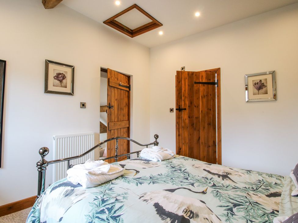A bedroom with a bed and doors at The Hay Loft in Craven Arms