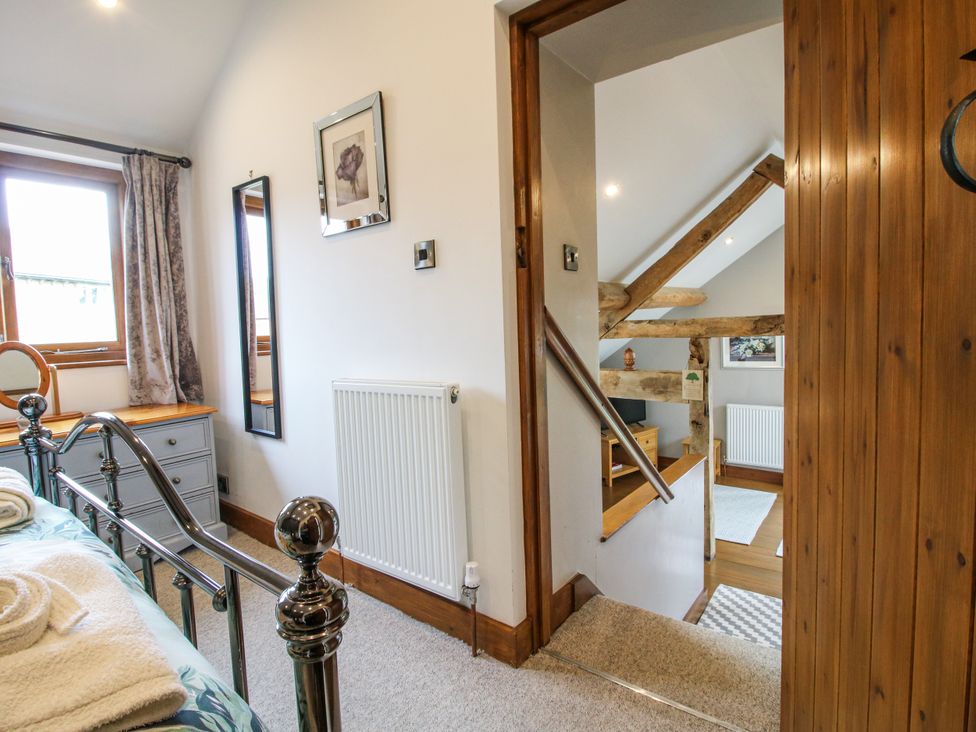 A bedroom with a bed, dressing table, and staircase at The Hay Loft in Craven Arms