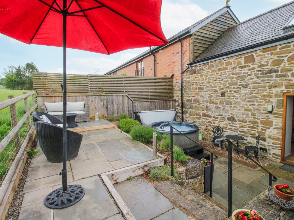 An outdoor area with a hot tub and seating at The Hay Loft in Craven Arms