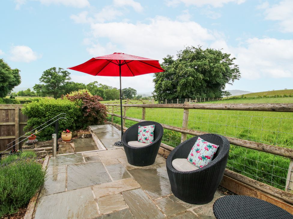 A garden area with chairs and an umbrella at The Hay Loft in Craven Arms