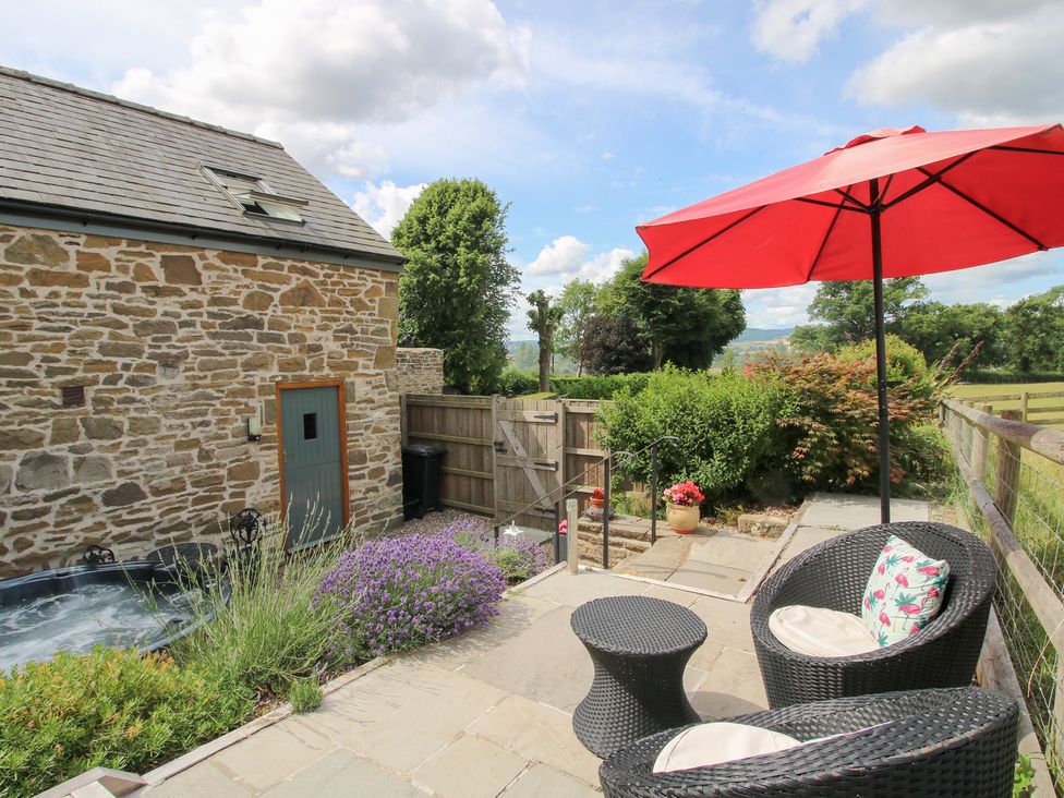 An outdoor area with a hot tub and seating at The Hay Loft in Craven Arms