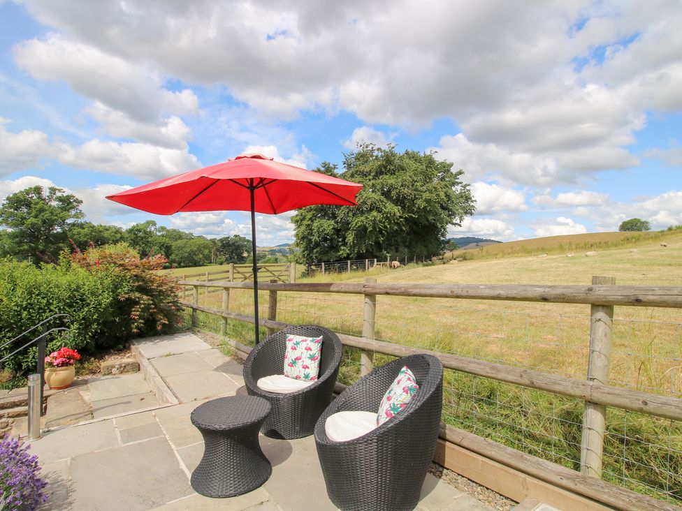 An outdoor seating area with two chairs and a red umbrella at The Hay Loft in Craven Arms