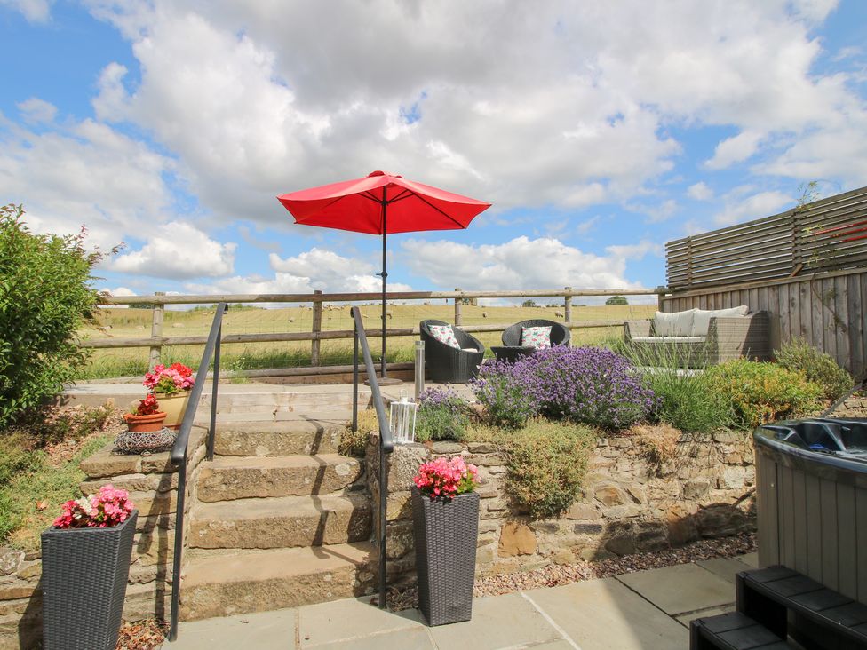 A garden area with outdoor furniture and an umbrella at The Hay Loft in Craven Arms