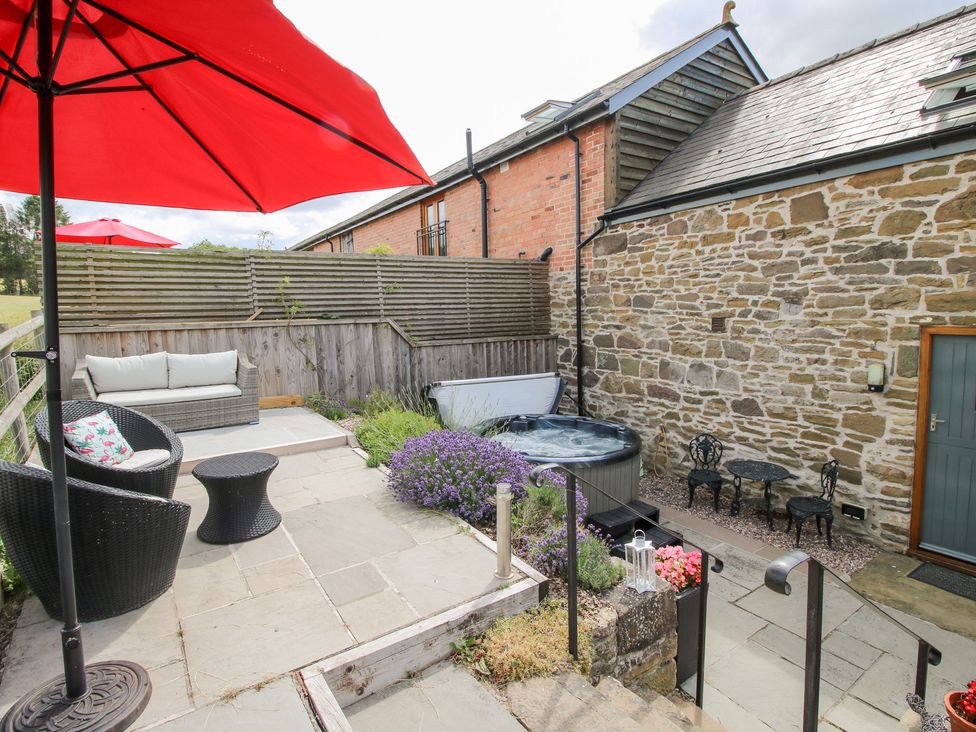 An outdoor area with a hot tub and seating at The Hay Loft in Craven Arms