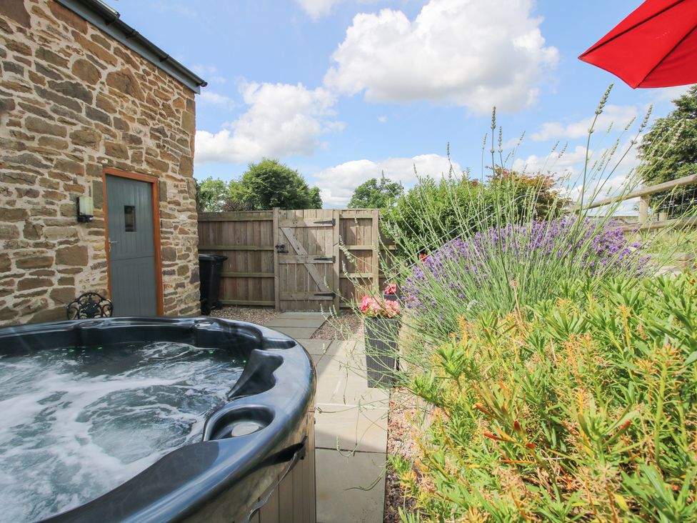 An outdoor area with a hot tub and plants at The Hay Loft in Craven Arms