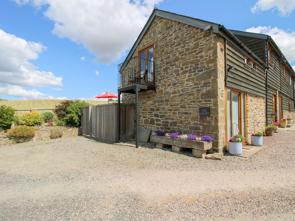 An outdoor view of a stone building with flower pots at The Hay Loft in Craven Arms
