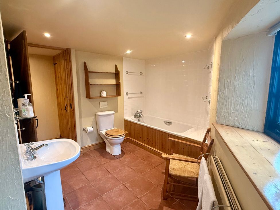 A bathroom with a bath tub and sink at Meadow Cottage in Golant, near Fowey